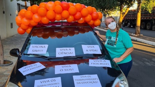 Professora enfeita o carro com bexigas e frases de agradecimento para receber a primeira dose da vacina contra Covid-19